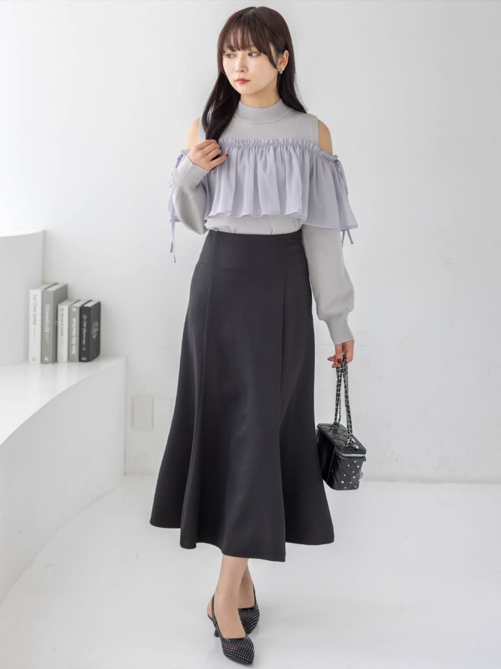ブラック系のスカート、ブラック系のパンプス、グレー系のニット/セーターを着用したレディースの夏コーディネートの1枚目の写真