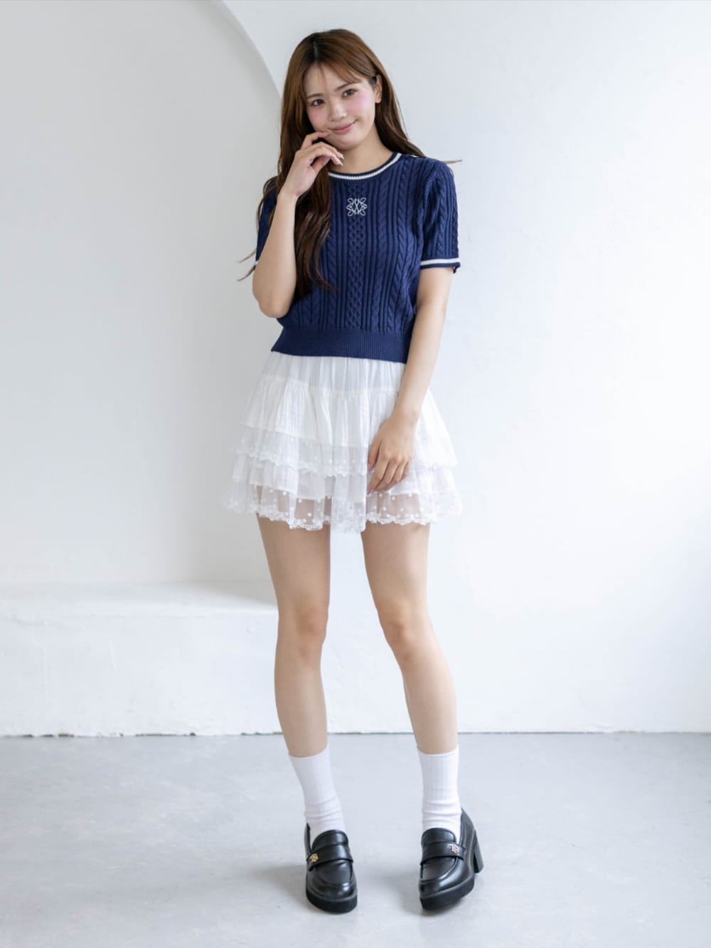 ブラック系のローファー、ホワイト系のスカート、ブルー系のニット/セーターを着用したレディースの夏コーディネートの1枚目の写真