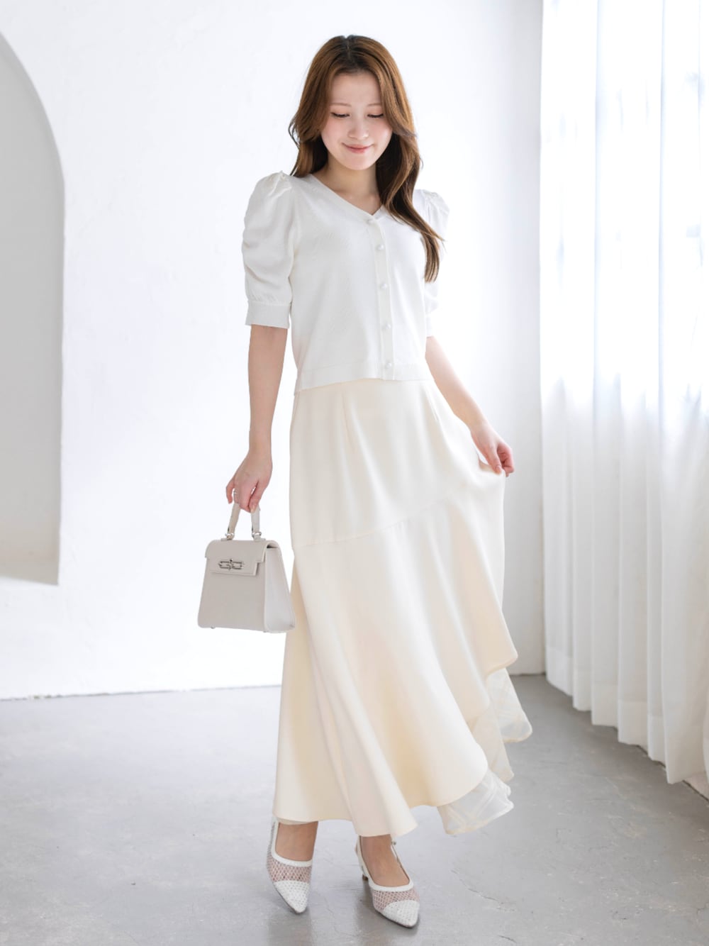 ホワイト系のスカート、ホワイト系のハンドバッグ、ホワイト系のパンプスを着用したレディースの春コーディネートの1枚目の写真