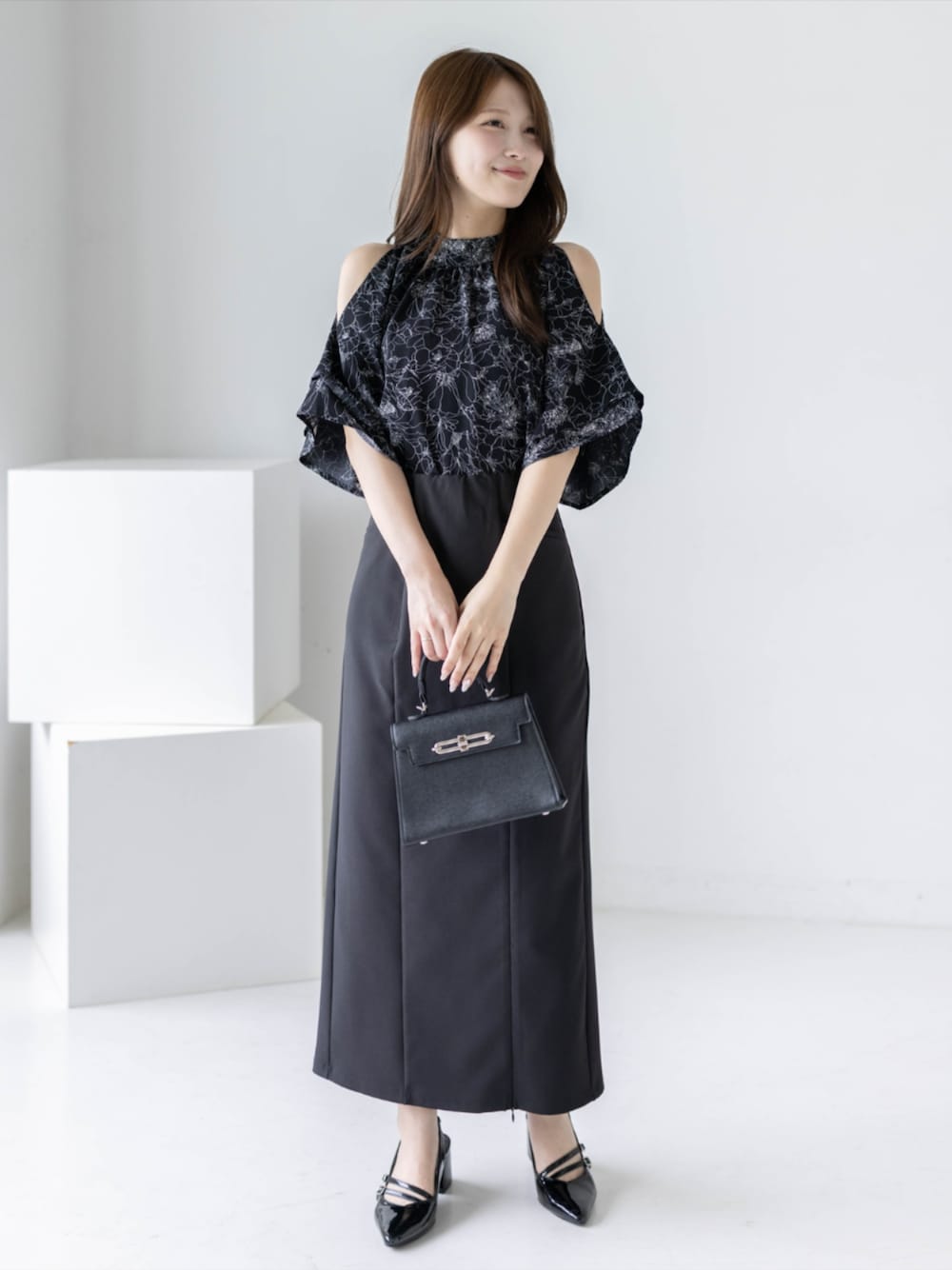 ブラック系のパンプス、ブラック系のハンドバッグ、ブラック系のスカートを着用したレディースの夏コーディネートの1枚目の写真
