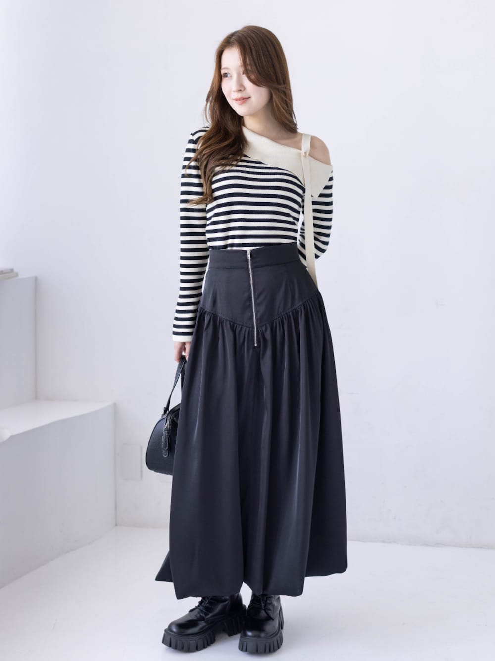 ブラック系のブーツ、ホワイト系のニット/セーター、ブラック系のスカートを着用したレディースの冬コーディネートの1枚目の写真