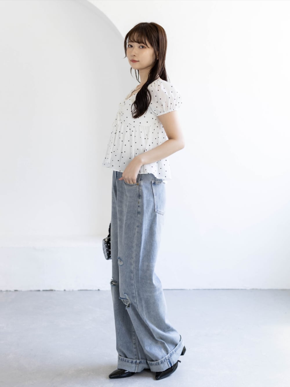 ブラック系のパンプス、ブルー系のデニムパンツ、ブラック系のボストンバッグを着用したレディースの夏コーディネートの1枚目の写真
