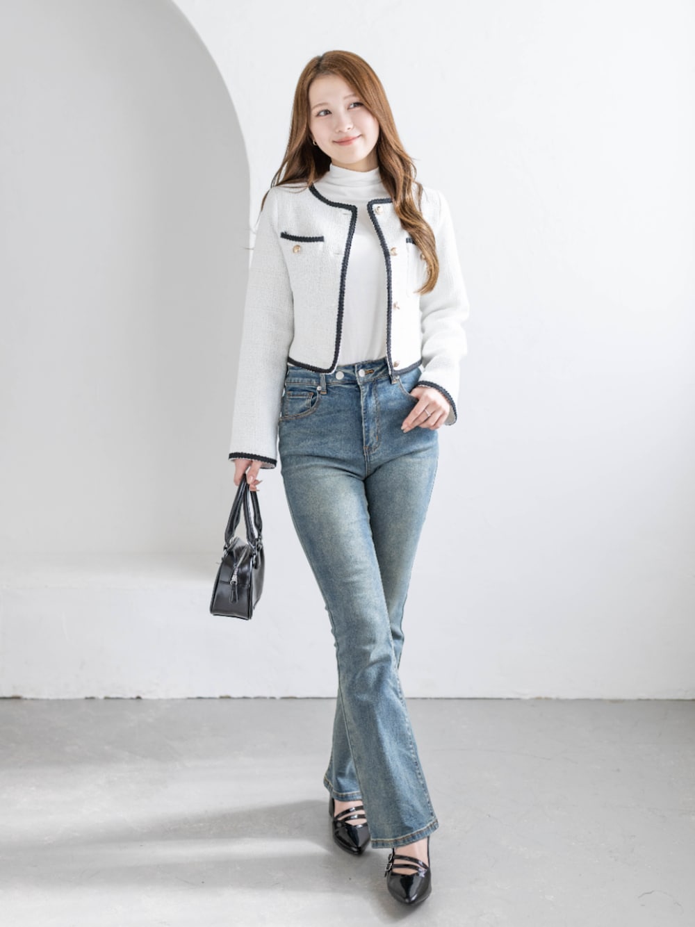 ブルー系のデニムパンツ、ブラック系のパンプス、ホワイト系のノーカラージャケットを着用したレディースの冬コーディネートの1枚目の写真