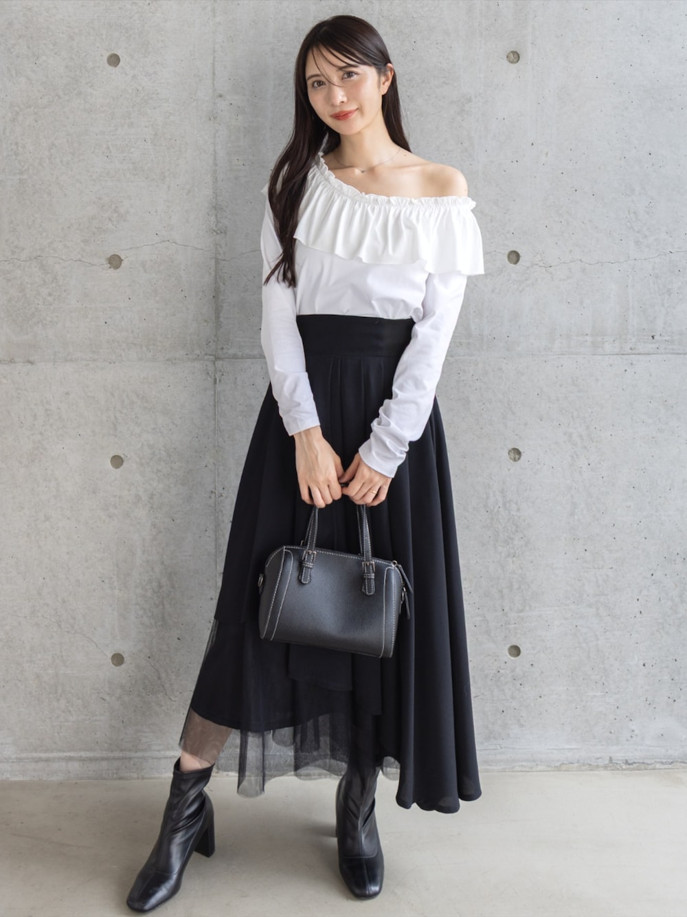 ブラック系のボストンバッグ、ブラック系のブーツ、ブラック系のスカートを着用したレディースの秋コーディネートの1枚目の写真