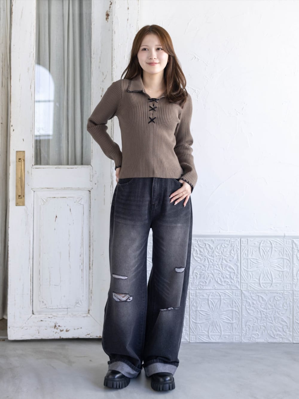ブラック系のデニムパンツ、ブラック系のブーツ、ブラウン系のニット/セーターを着用したレディースの秋コーディネートの1枚目の写真