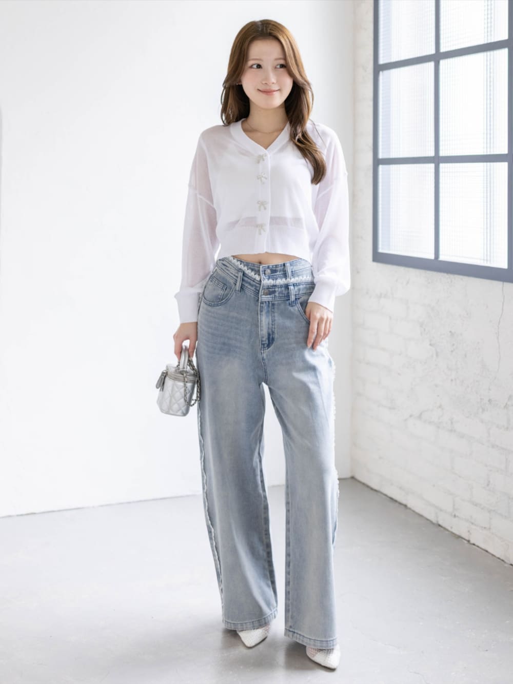 ブルー系のデニムパンツ、ホワイト系のパンプス、ホワイト系のカーディガン/ボレロを着用したレディースの春コーディネートの1枚目の写真