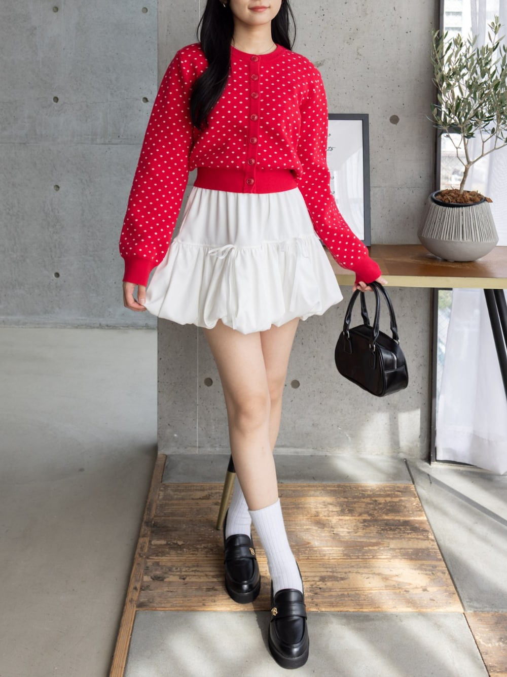 ブラック系のハンドバッグ、ブラック系のローファー、ホワイト系のスカートを着用したレディースの秋コーディネートの1枚目の写真