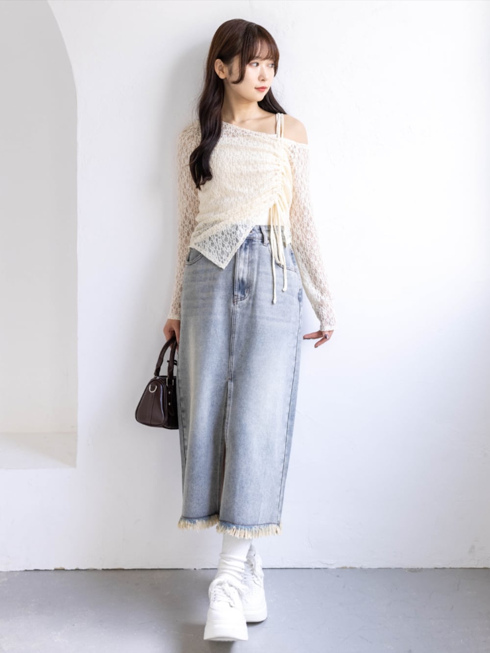 ブラウン系のボストンバッグ、ホワイト系のスニーカー、ブルー系のスカートを着用したレディースの春コーディネートの1枚目の写真