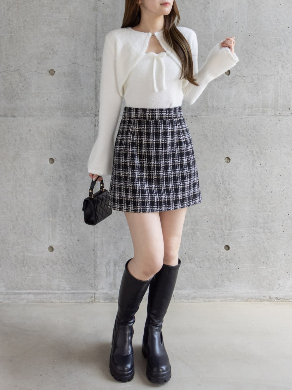 ブラック系のブーツ、ブラック系のショルダーバッグ、ブラック系のスカートを着用したレディースの秋コーディネートの1枚目の写真