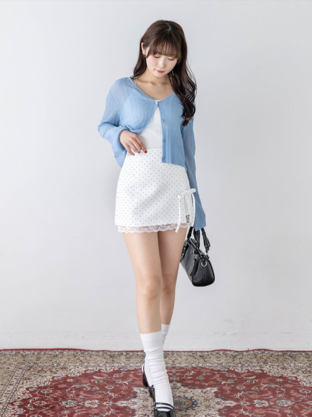 ブラック系のパンプス、ブラック系のハンドバッグ、グレー系のカーディガン/ボレロを着用したレディースの春コーディネートの1枚目の写真