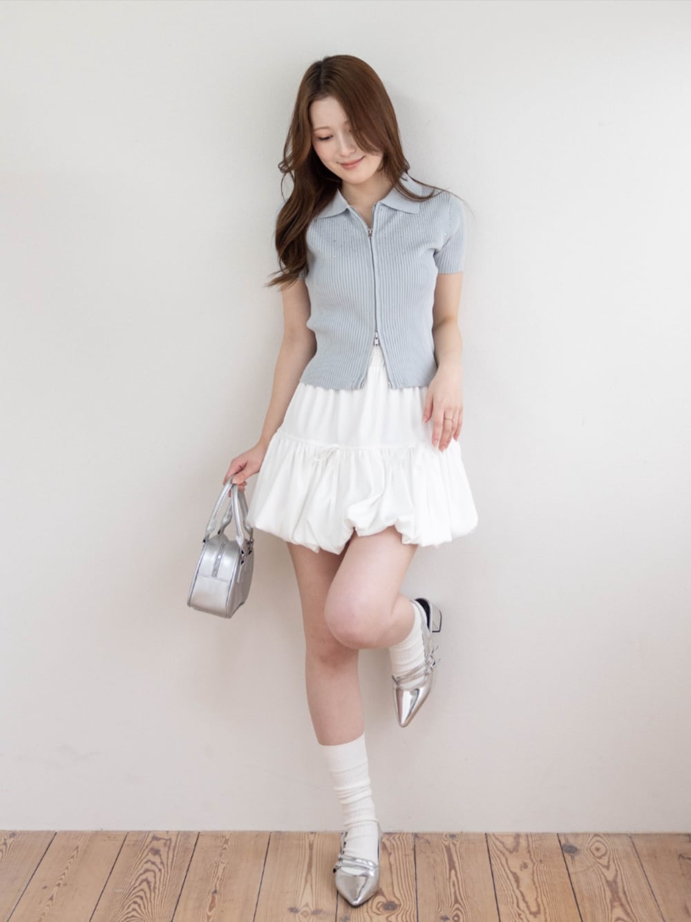 シルバー系のパンプス、ホワイト系のスカート、グレー系のニット/セーターを着用したレディースの春コーディネートの1枚目の写真