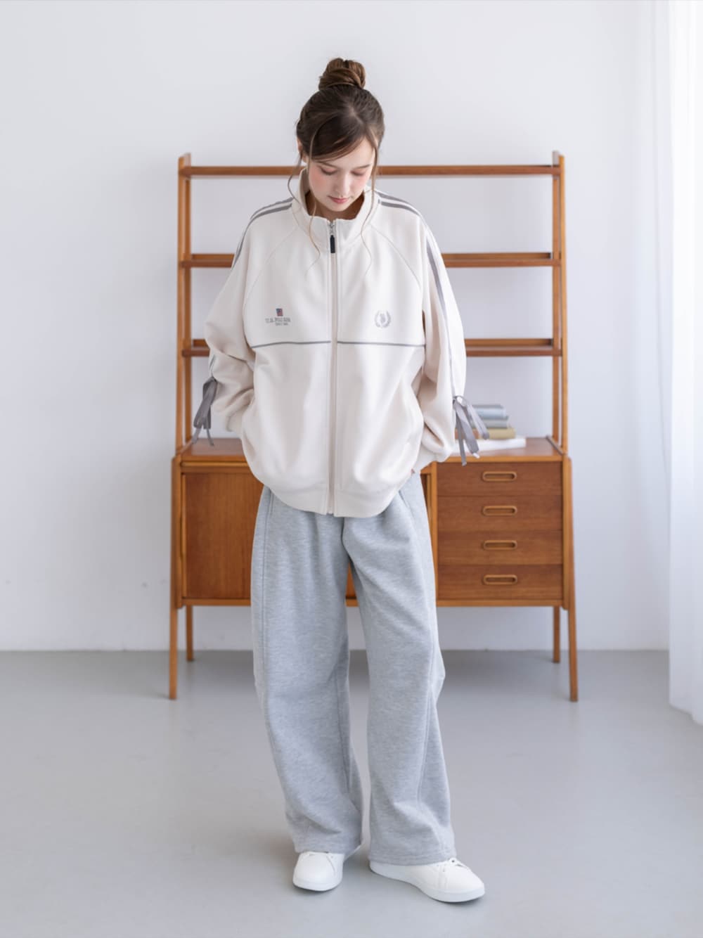 ゴールド系のスニーカー、グレー系のスウェットパンツ、ホワイト系のTシャツ/カットソーを着用したレディースの秋コーディネートの1枚目の写真