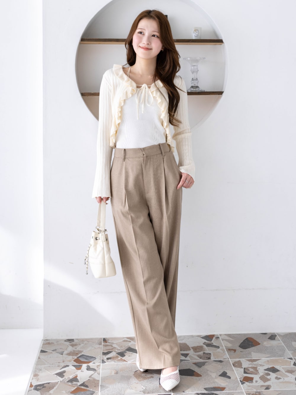 ベージュ系のその他パンツ、ホワイト系のカーディガン/ボレロ、ホワイト系のハンドバッグを着用したレディースの冬コーディネートの1枚目の写真