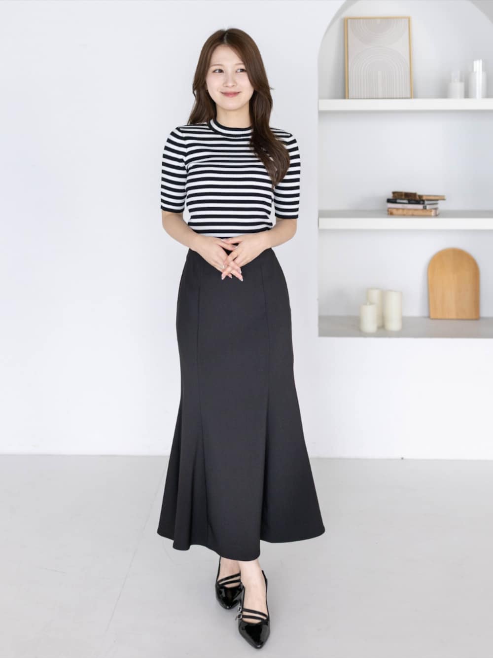 ブラック系のニット/セーター、ブラック系のパンプス、ブラック系のスカートを着用したレディースの夏コーディネートの1枚目の写真