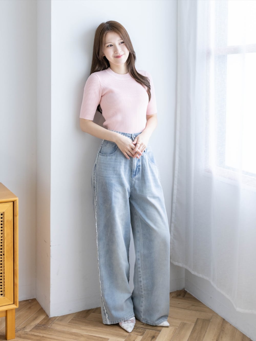 ピンク系のニット/セーター、ブルー系のデニムパンツ、ホワイト系のパンプスを着用したレディースの夏コーディネートの1枚目の写真