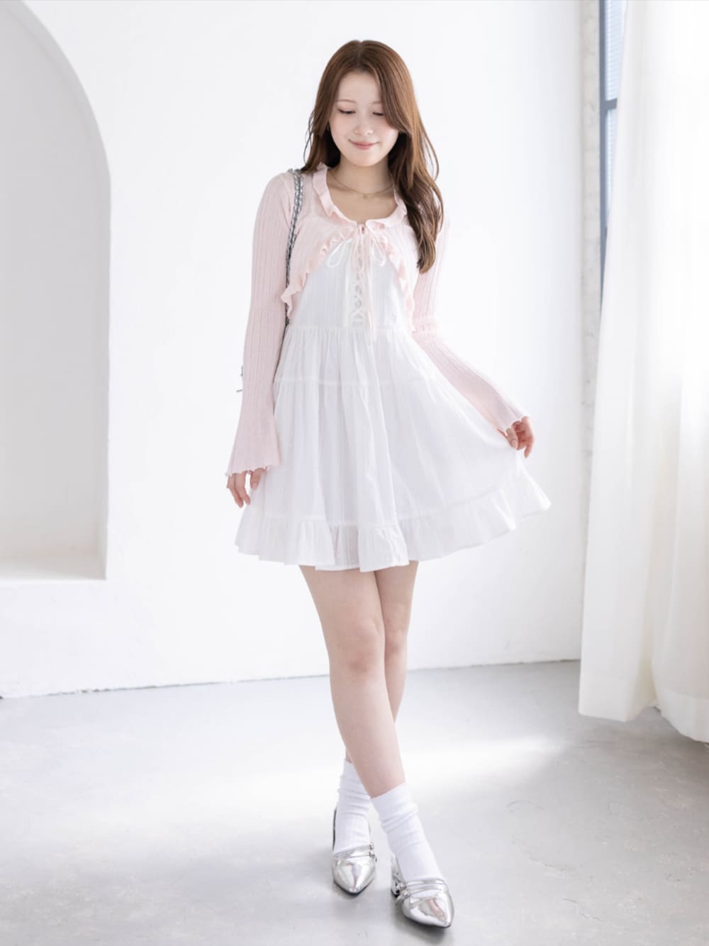 シルバー系のパンプス、ホワイト系のワンピース、ピンク系のカーディガン/ボレロを着用したレディースの春コーディネートの1枚目の写真