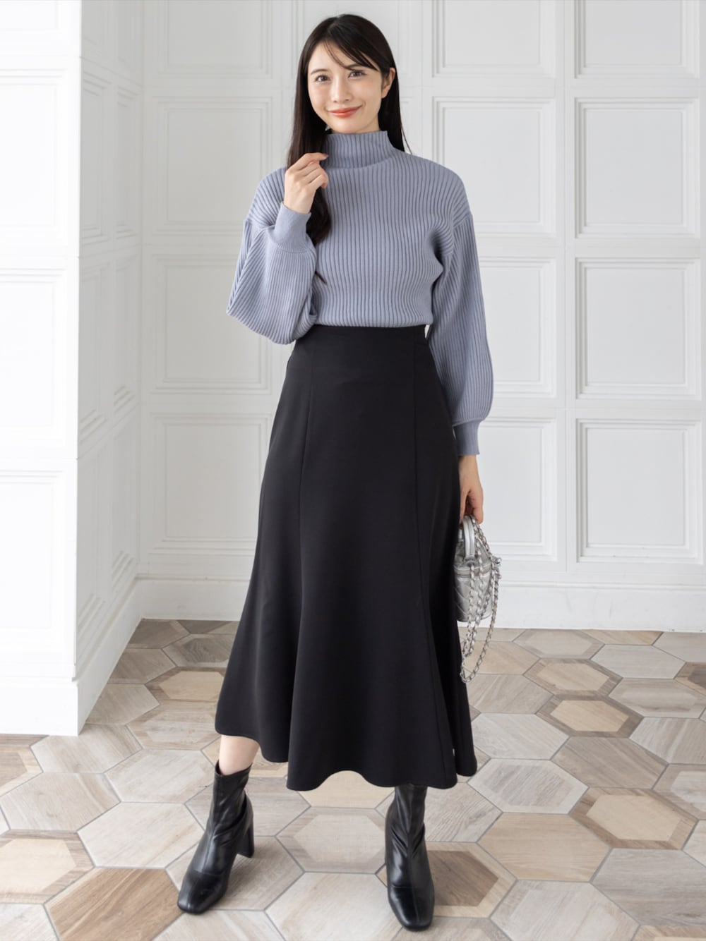ブラック系のブーツ、ブラック系のスカート、グレー系のニット/セーターを着用したレディースの秋コーディネートの1枚目の写真
