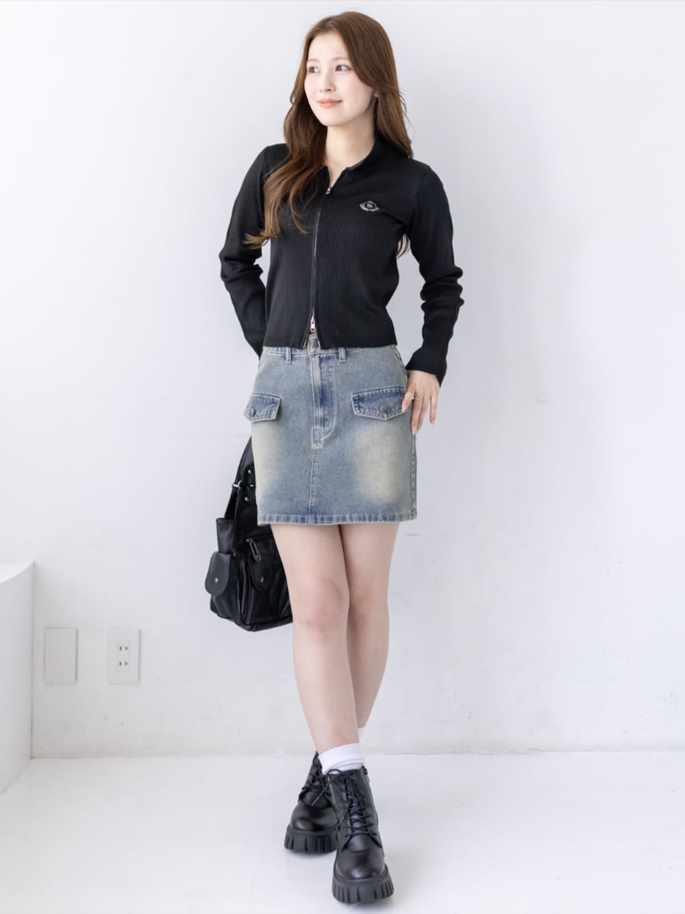 ブラック系のブーツ、ブルー系のデニムスカート、ブラック系のニット/セーターを着用したレディースの夏コーディネートの1枚目の写真