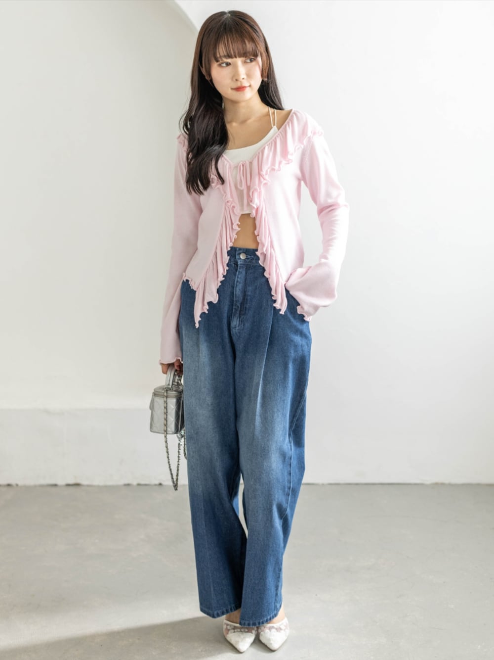 ホワイト系のパンプス、ブルー系のデニムパンツ、ピンク系のカーディガン/ボレロを着用したレディースの春コーディネートの1枚目の写真