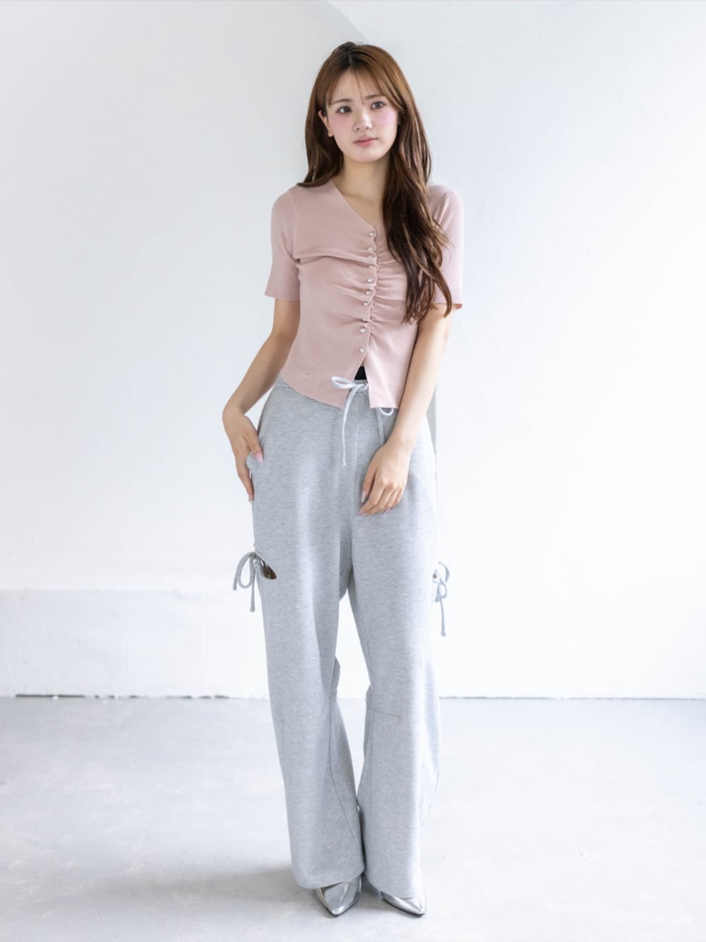 シルバー系のパンプス、グレー系のスウェットパンツ、ピンク系のカーディガン/ボレロを着用したレディースの春コーディネートの1枚目の写真