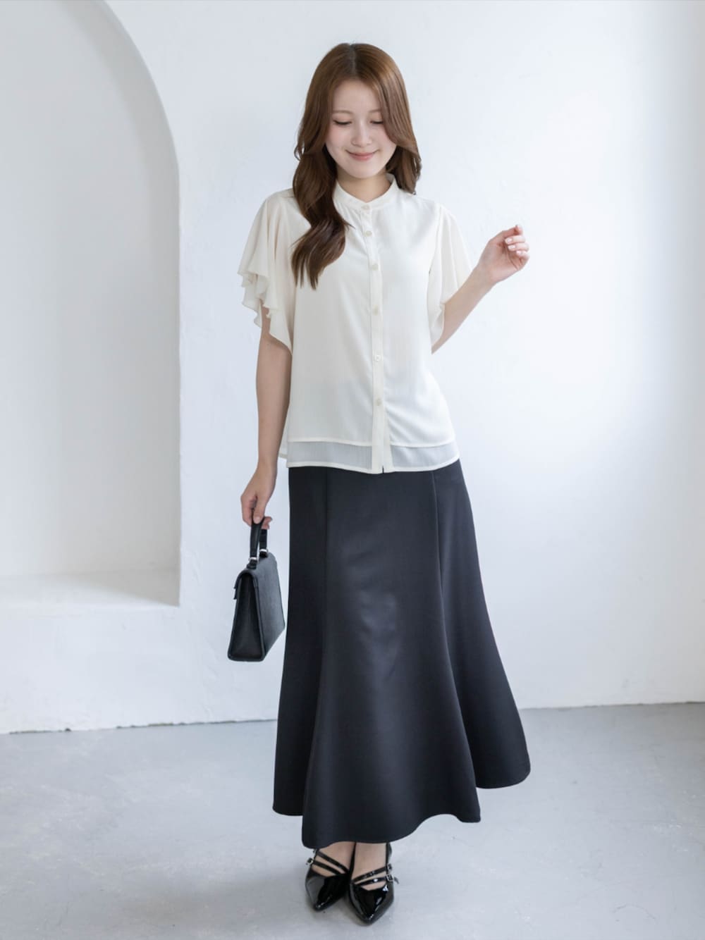 ブラック系のパンプス、ブラック系のスカート、ホワイト系のシャツ/ブラウスを着用したレディースの夏コーディネートの1枚目の写真