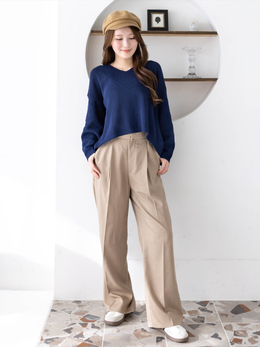 ホワイト系のスニーカー、ベージュ系のスラックス、ブルー系のニット/セーターを着用したレディースの春コーディネートの1枚目の写真