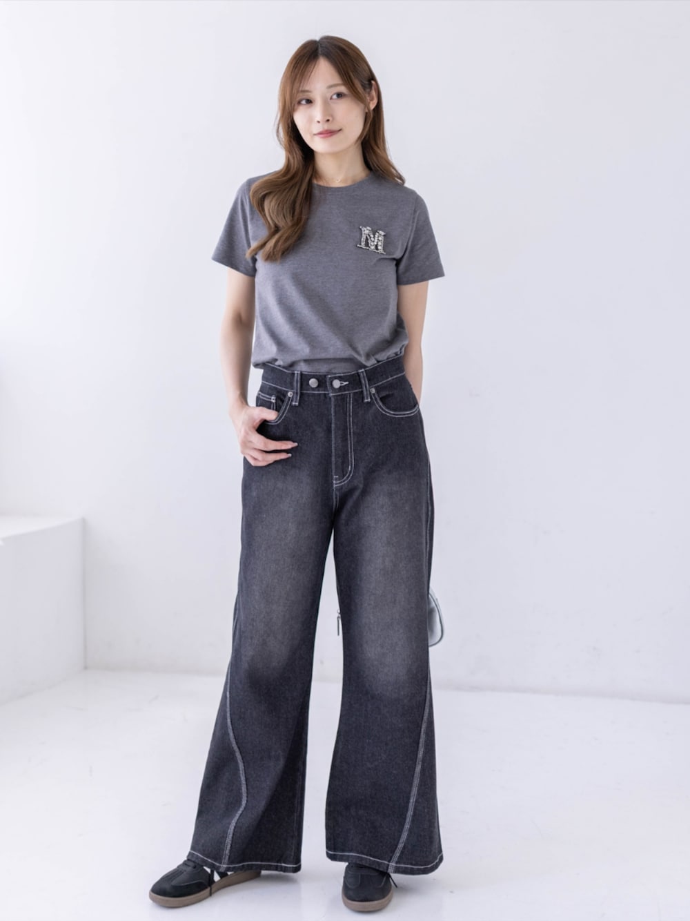 ブラック系のスニーカー、ブラック系のデニムパンツ、グレー系のTシャツ/カットソーを着用したレディースの春コーディネートの1枚目の写真