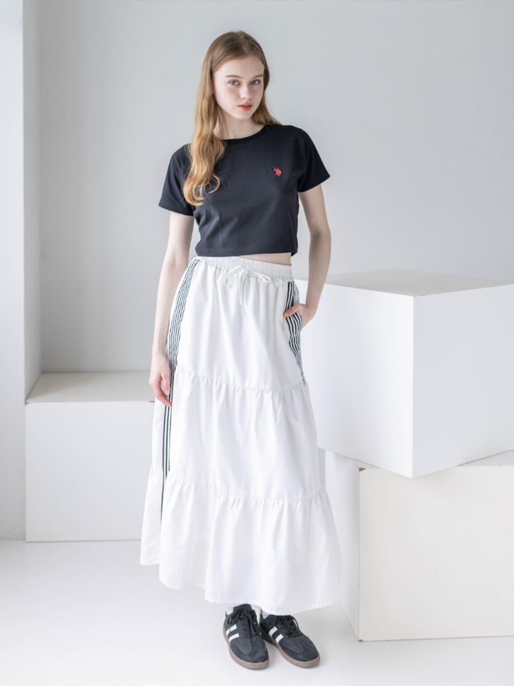 ブラック系のスニーカー、ホワイト系のスカート、ブラック系のTシャツ/カットソーを着用したレディースの夏コーディネートの1枚目の写真