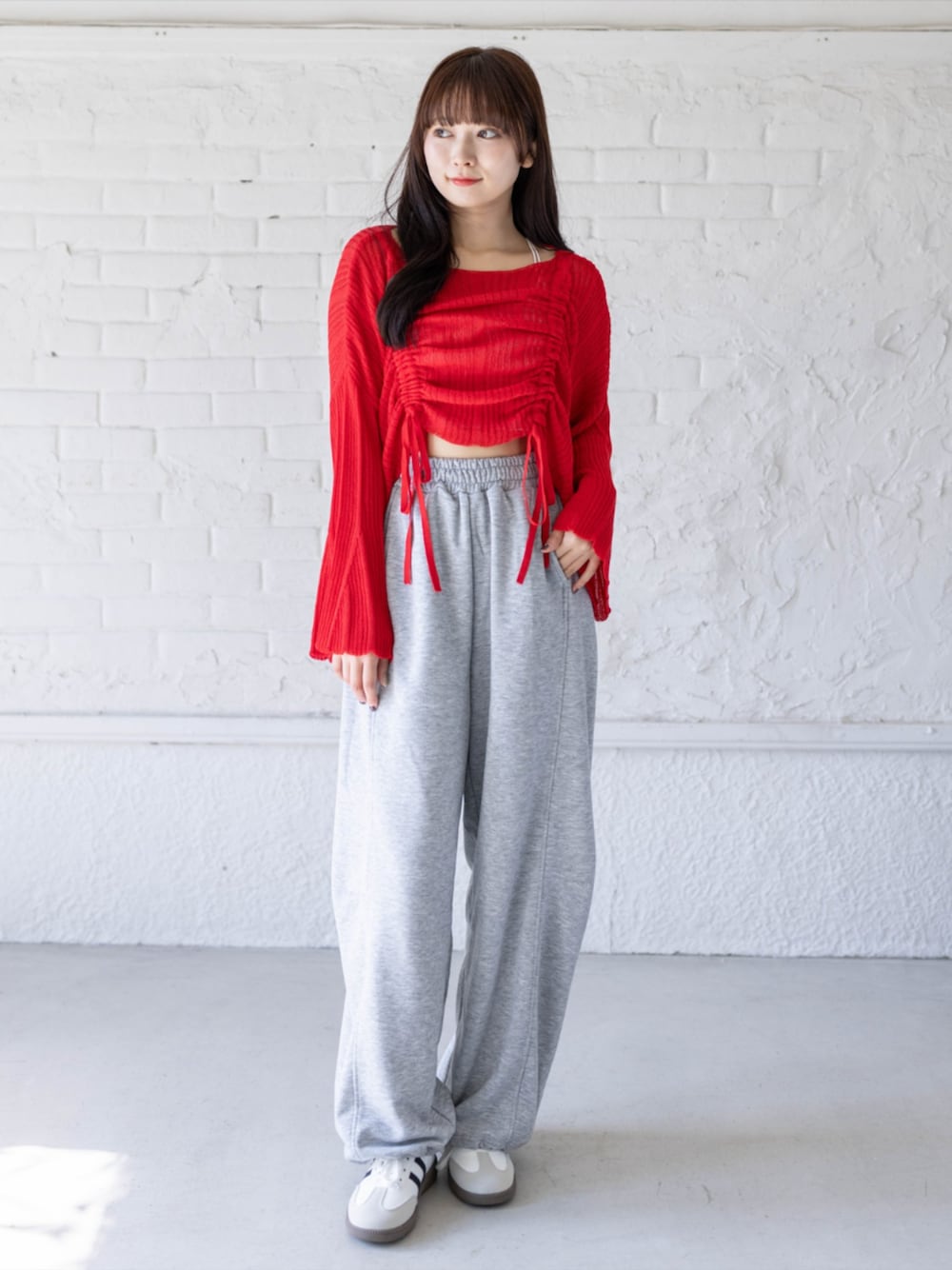 ホワイト系のスニーカー、グレー系のスウェットパンツ、レッド系のニット/セーターを着用したレディースの春コーディネートの1枚目の写真