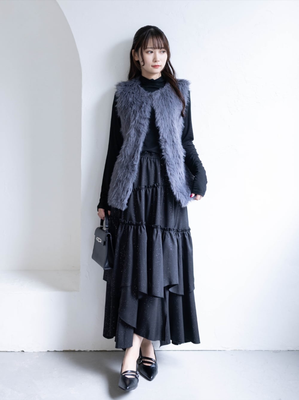 ブラック系のハンドバッグ、ブラック系のTシャツ/カットソー、グレー系のスカートを着用したレディースの秋コーディネートの1枚目の写真