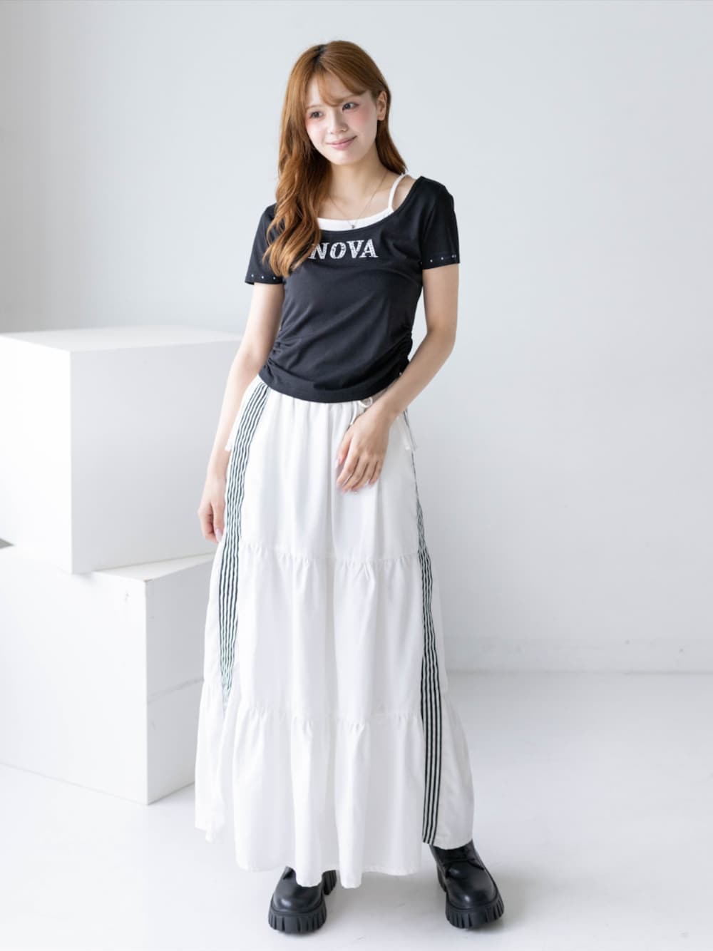 ブラック系のブーツ、ホワイト系のスカート、ブラック系のTシャツ/カットソーを着用したレディースの夏コーディネートの1枚目の写真