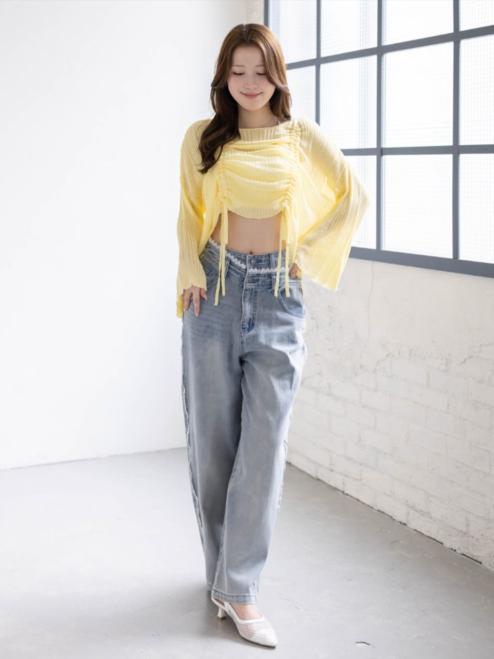 ブルー系のデニムパンツ、ホワイト系のパンプス、イエロー系のニット/セーターを着用したレディースの春コーディネートの1枚目の写真