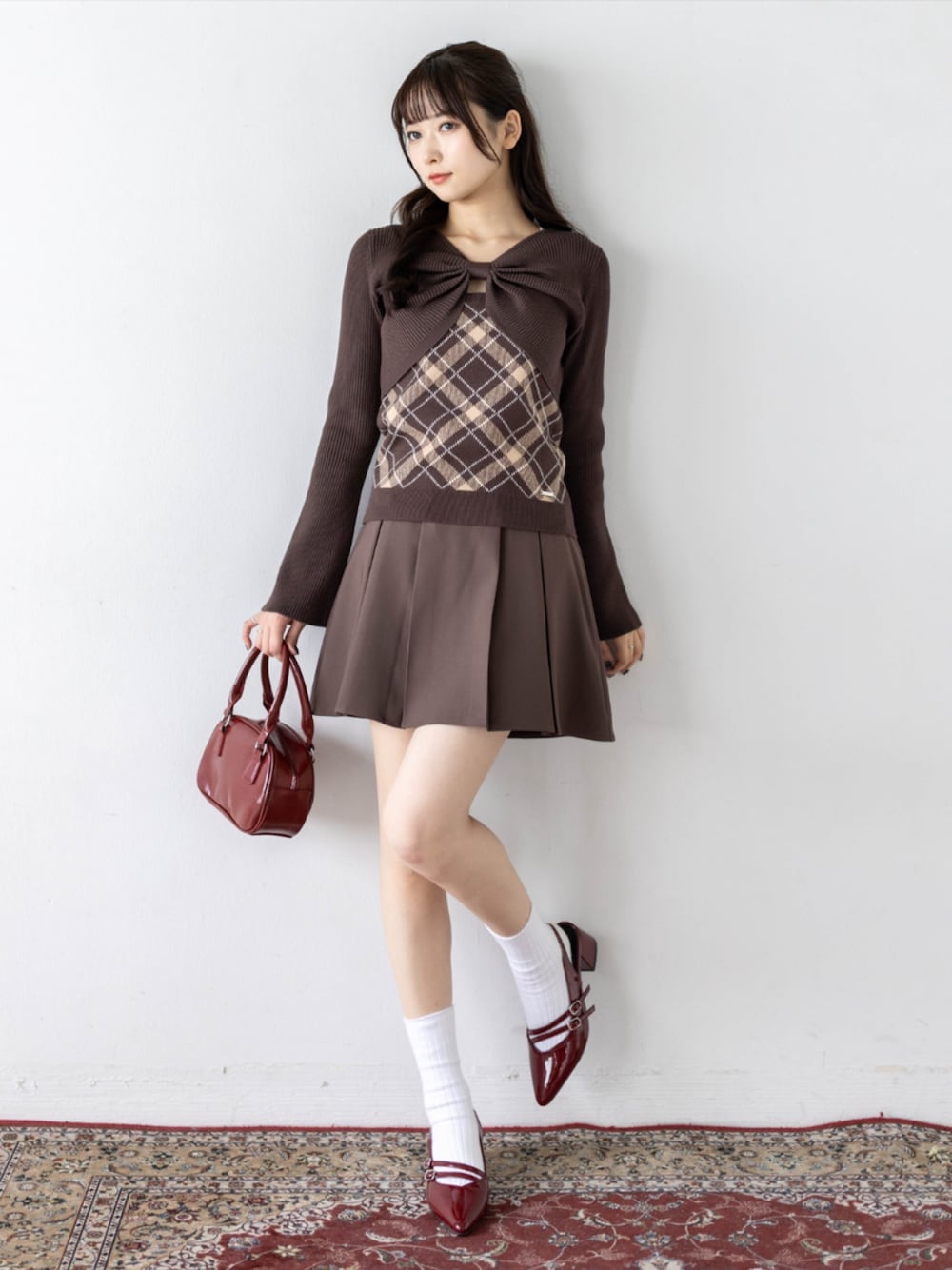 レッド系のパンプス、ブラウン系のスカート、ブラウン系のニット/セーターを着用したレディースの秋コーディネートの1枚目の写真
