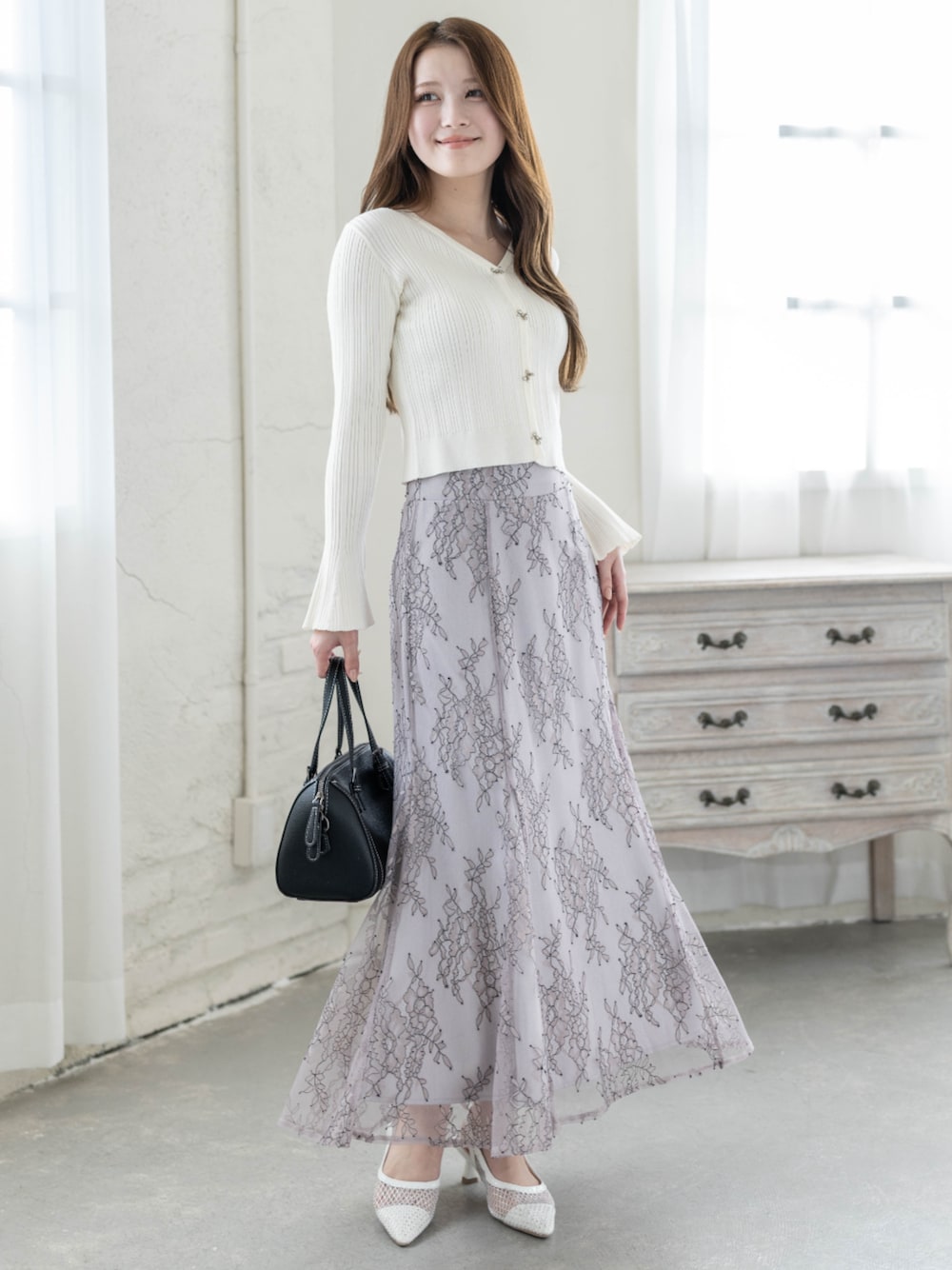 ホワイト系のカーディガン/ボレロ、グレー系のスカートを着用したレディースの冬コーディネートの1枚目の写真