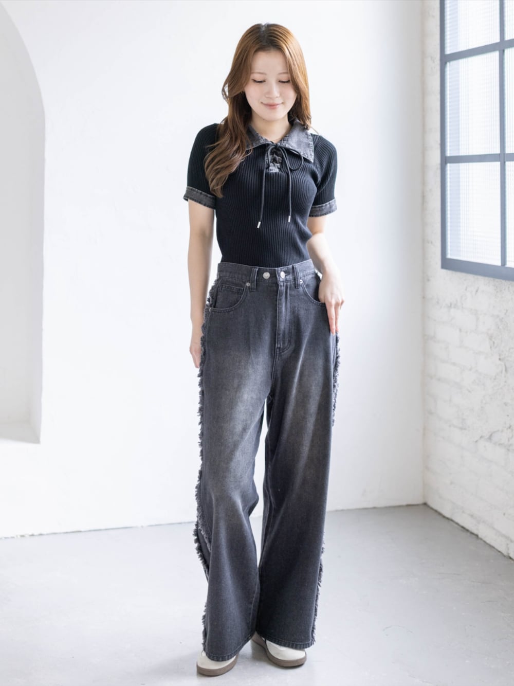 ホワイト系のスニーカー、ブラック系のデニムパンツ、ブラック系のニット/セーターを着用したレディースの春コーディネートの1枚目の写真