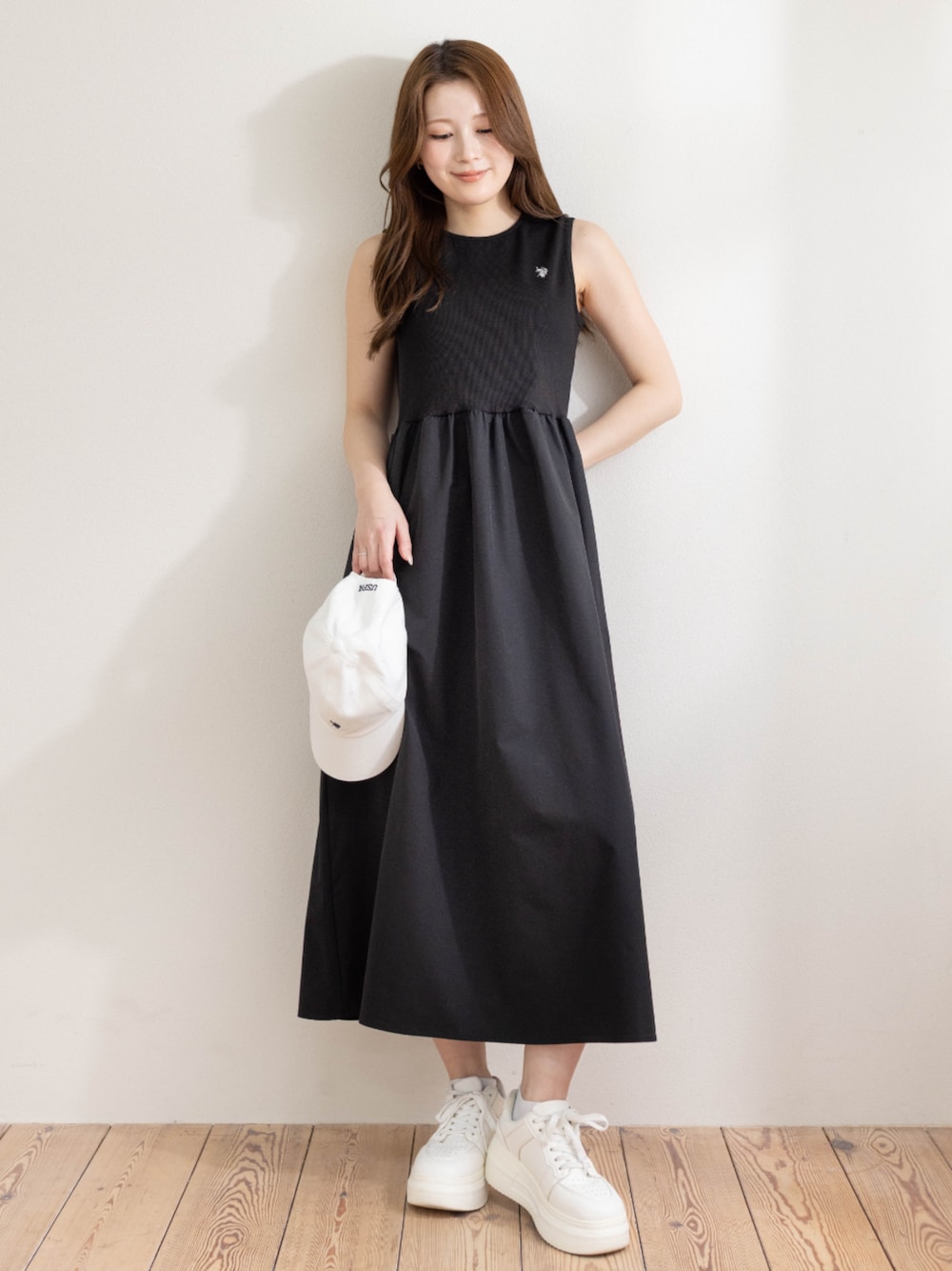 ブラック系のワンピース、ホワイト系のキャップを着用したレディースの春コーディネートの1枚目の写真