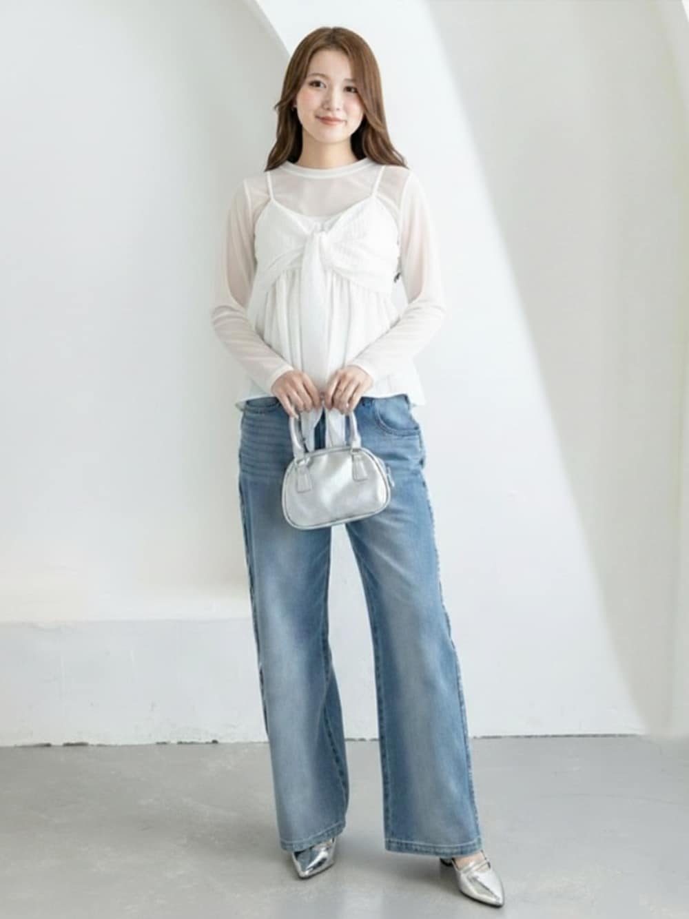 シルバー系のパンプス、ブルー系のデニムパンツ、ホワイト系のキャミソールを着用したレディースの冬コーディネートの1枚目の写真