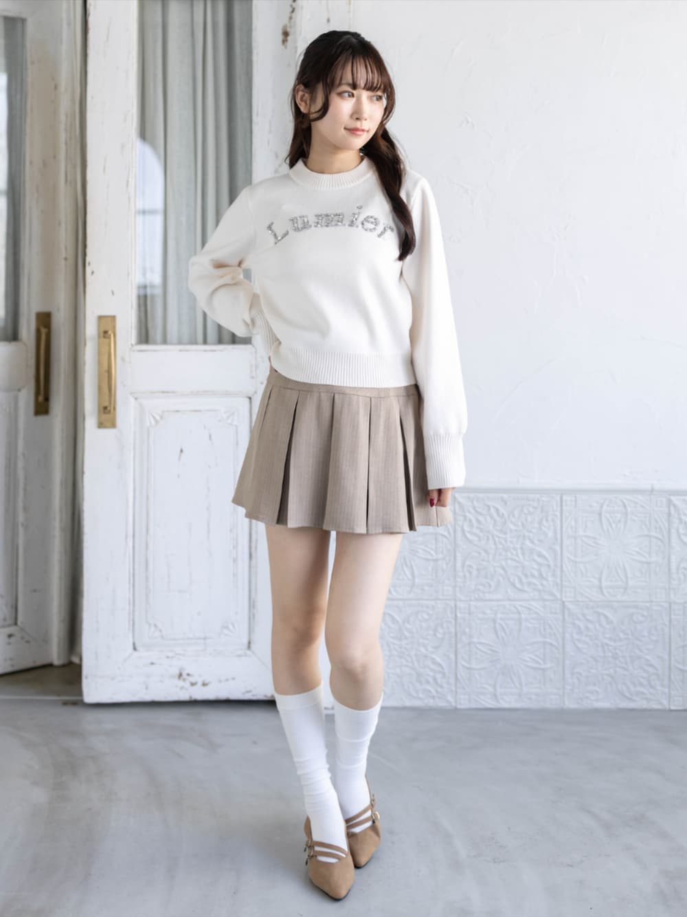 ベージュ系のスカート、イエロー系のパンプス、ホワイト系のニット/セーターを着用したレディースの秋コーディネートの1枚目の写真