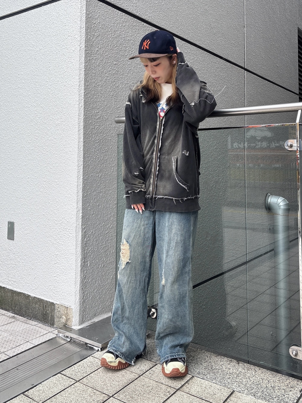 ブラック系のパーカー、ブルー系のデニムパンツ、ブラック系のスニーカーを着用したレディースの秋コーディネートの1枚目の写真