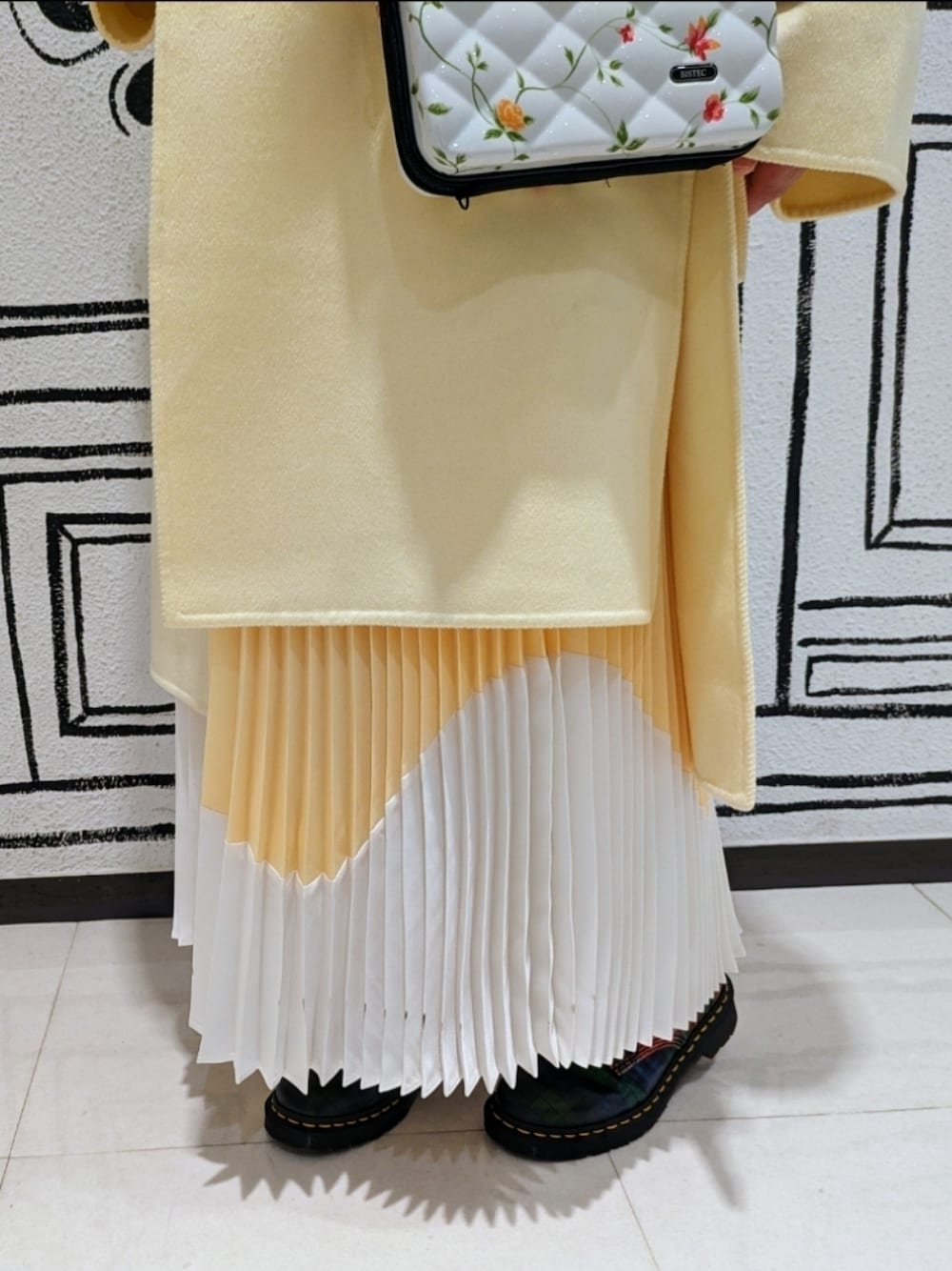 イエロー系のノーカラーコート、イエロー系のスカート、ホワイト系のシャツ/ブラウスを着用したレディースの秋コーディネートの1枚目の写真