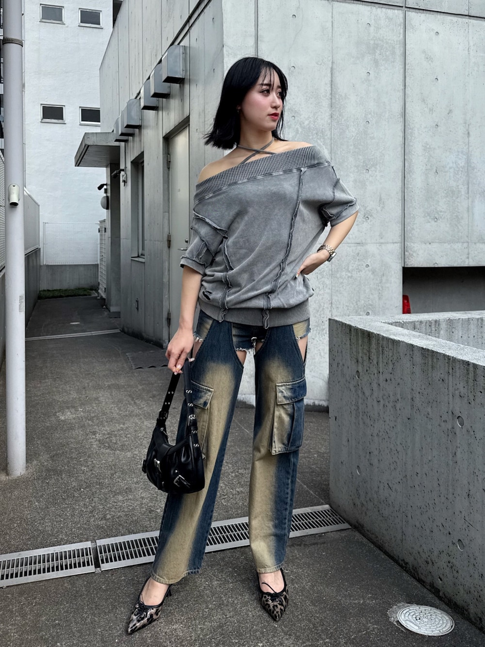 グレー系のワンピース、ブルー系のデニムパンツ、ブラック系のハンドバッグを着用したレディースの春コーディネートの1枚目の写真