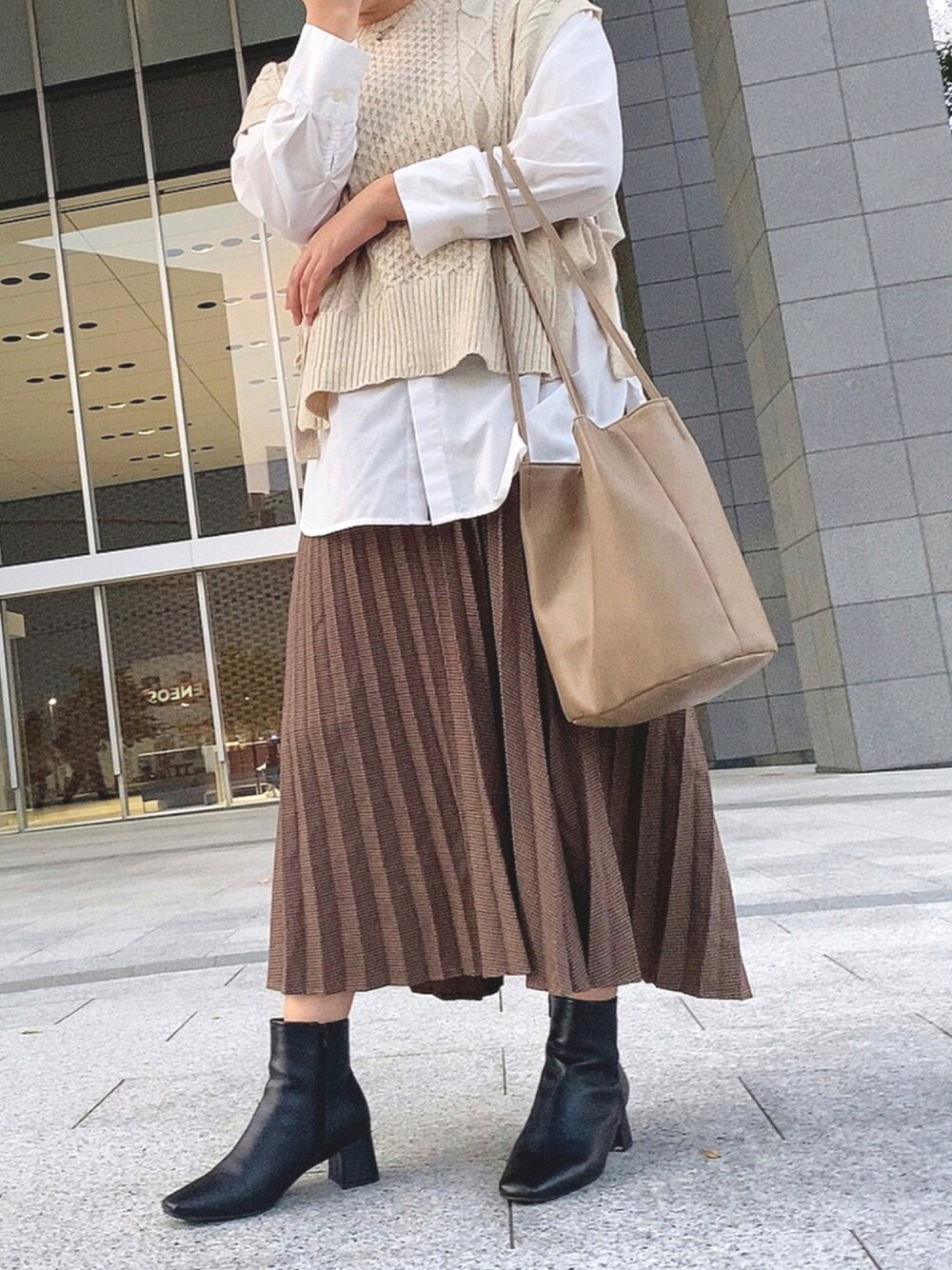 ベージュ系のスカート、ホワイト系のシャツ/ブラウス、ベージュ系のベストを着用したレディースの秋コーディネートの1枚目の写真
