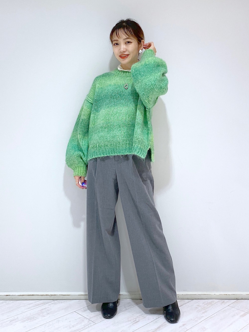 グレー系のその他パンツ、ブラック系のブーツ、グリーン系のニット/セーターを着用したレディースの秋コーディネートの1枚目の写真