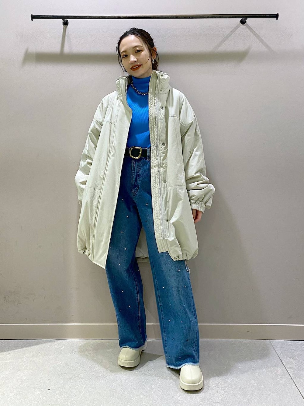 ホワイト系のダウンジャケット/コート、ブルー系のニット/セーター、ホワイト系のブーツを着用したレディースの冬コーディネートの1枚目の写真