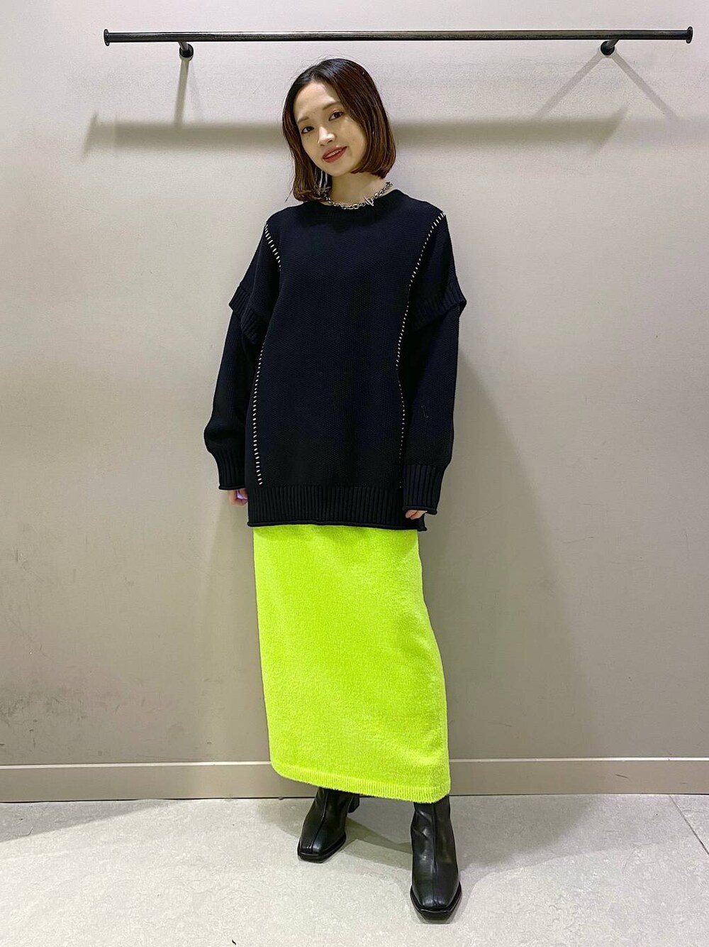 ブラック系のTシャツ/カットソー、ブラック系のパンプス、グリーン系のスカートを着用したレディースの秋コーディネートの1枚目の写真