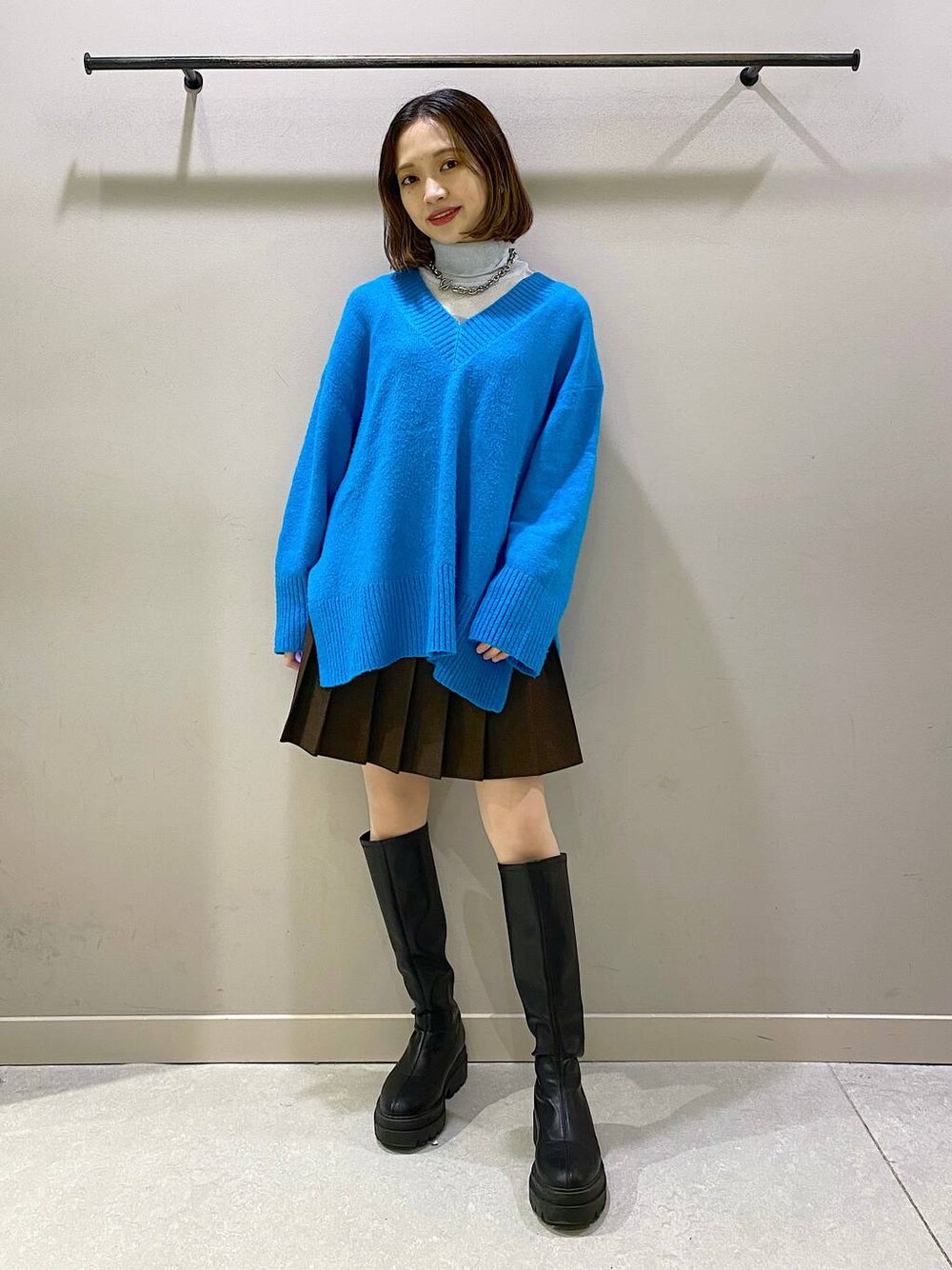 ブラウン系のスカート、ブルー系のニット/セーター、ブラック系のブーツを着用したレディースの秋コーディネートの1枚目の写真