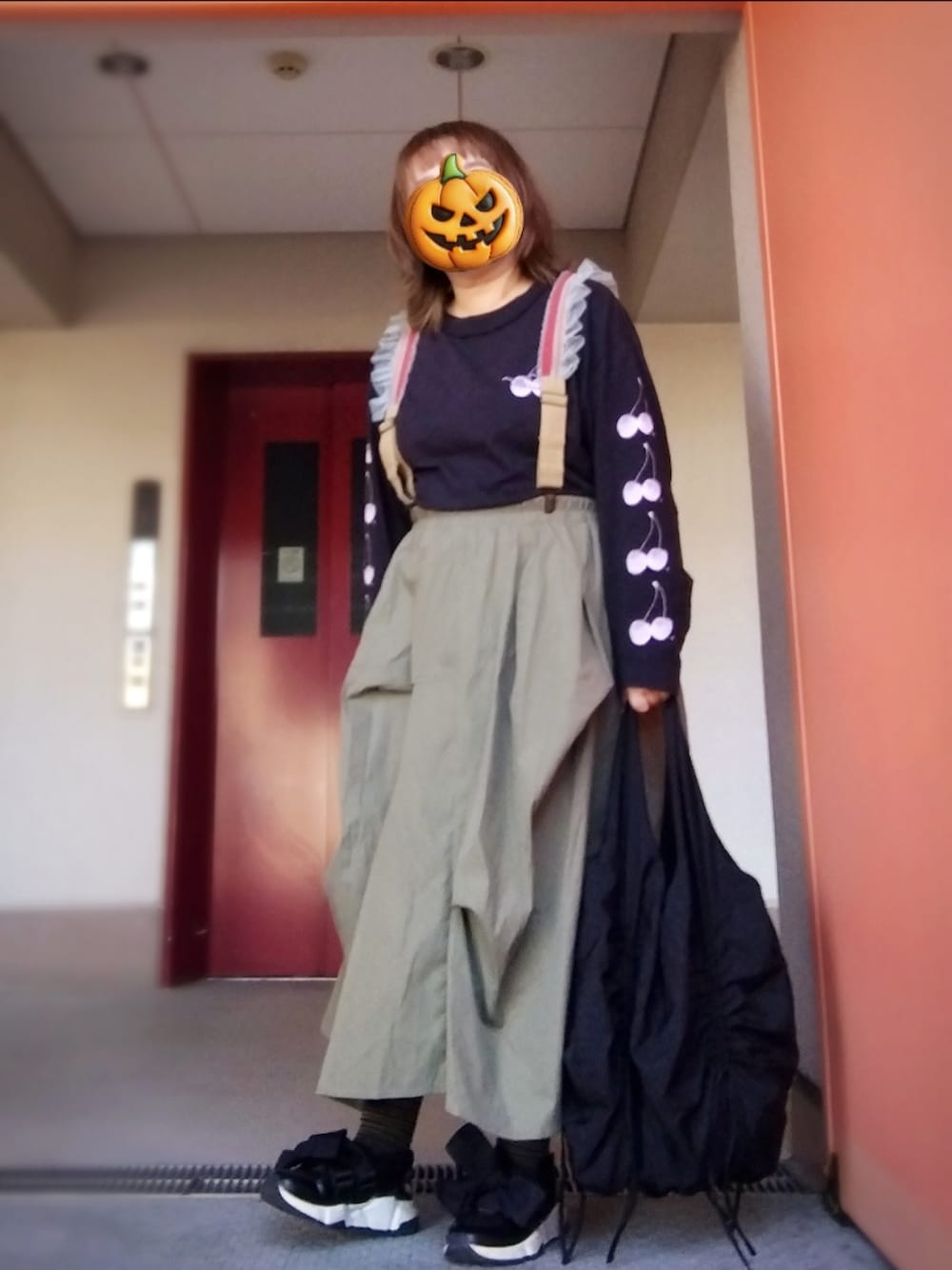 ブラック系のTシャツ/カットソー、グリーン系のスカート、ブラック系のショルダーバッグを着用したレディースの秋コーディネートの1枚目の写真