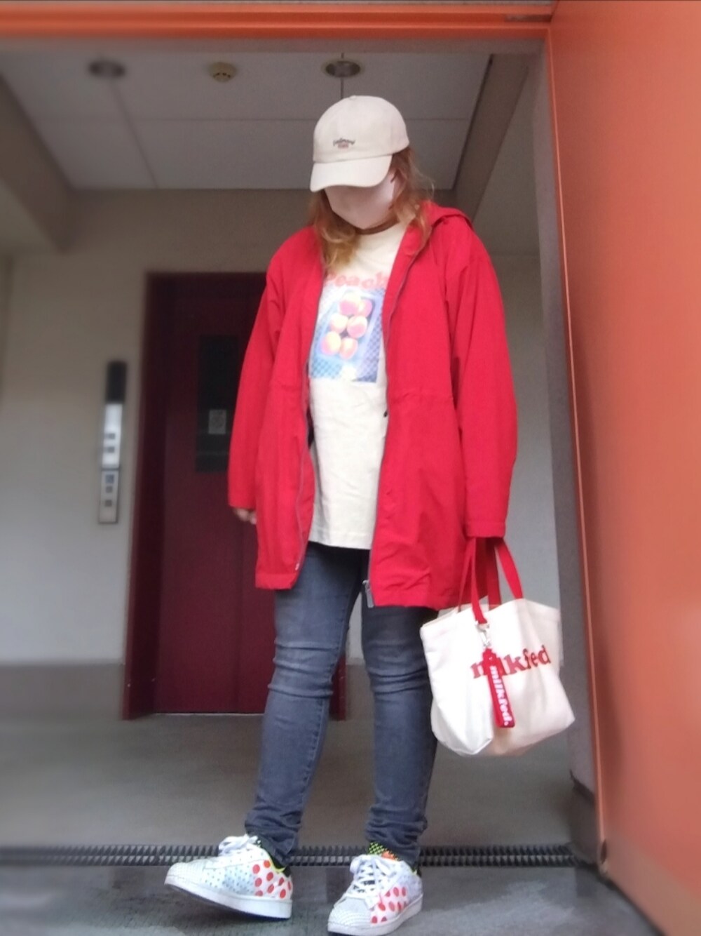 レッド系のマウンテンパーカー、ベージュ系のTシャツ/カットソー、グレー系のデニムパンツを着用したレディースの秋コーディネートの1枚目の写真