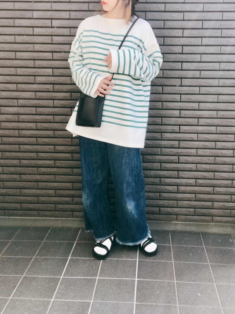 グリーン系のTシャツ/カットソー、ブルー系のデニムパンツ、ブラック系のサンダルを着用したレディースの春コーディネートの1枚目の写真