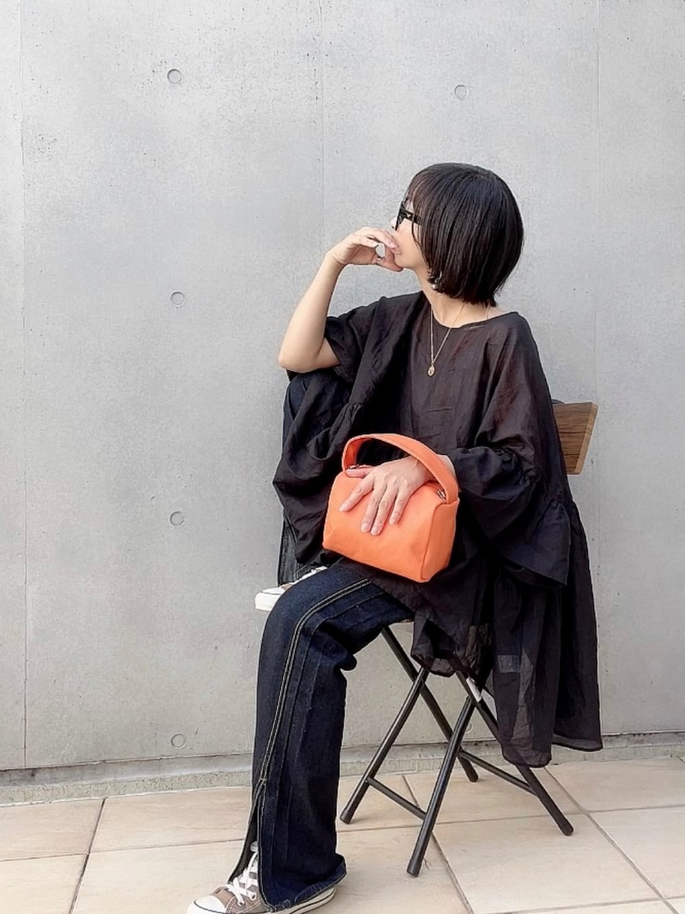 ブラック系のシャツ/ブラウス、オレンジ系のハンドバッグ、ブルー系のデニムパンツを着用したレディースの秋コーディネートの1枚目の写真